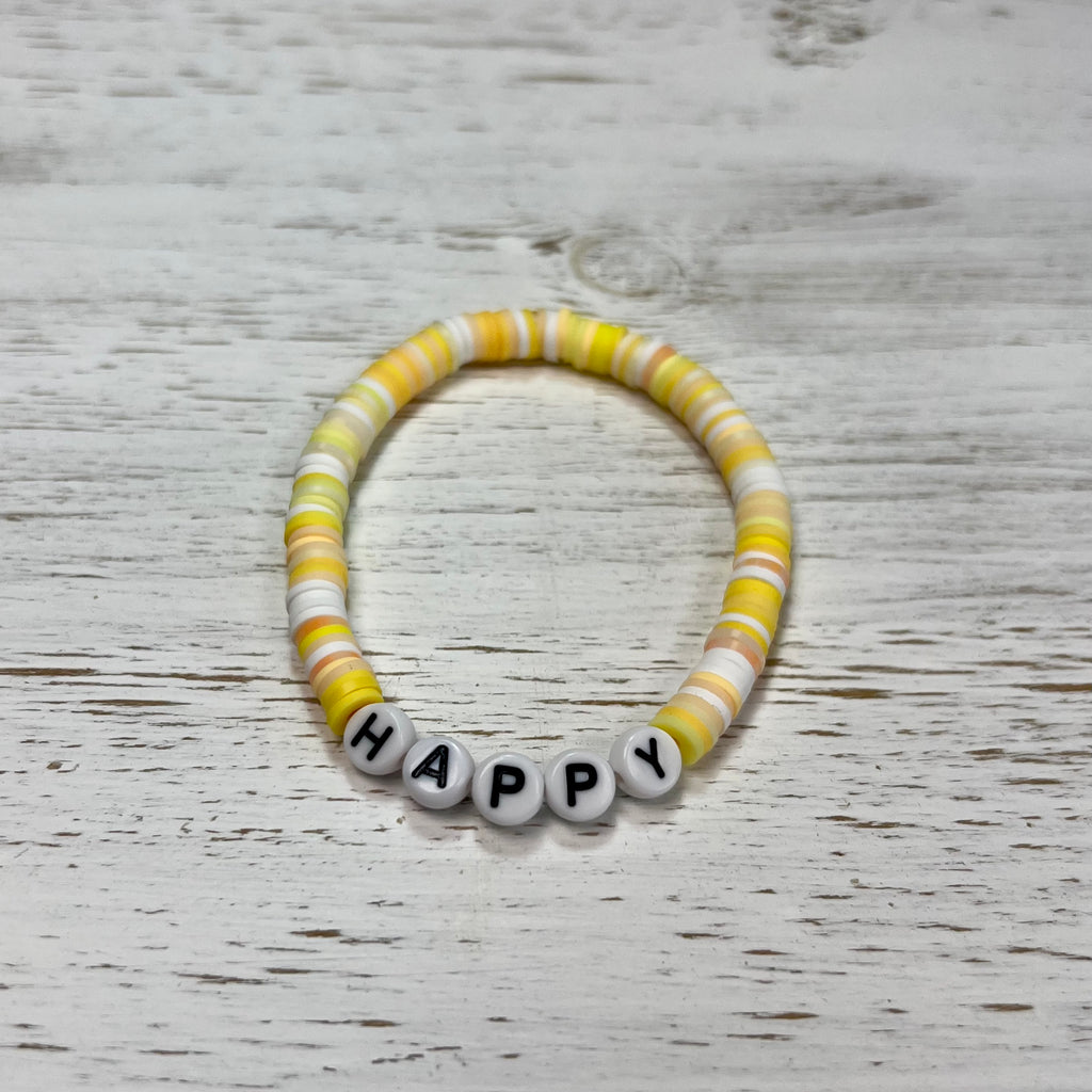 Beaded bracelet with 'HAPPY' beads on a wooden surface