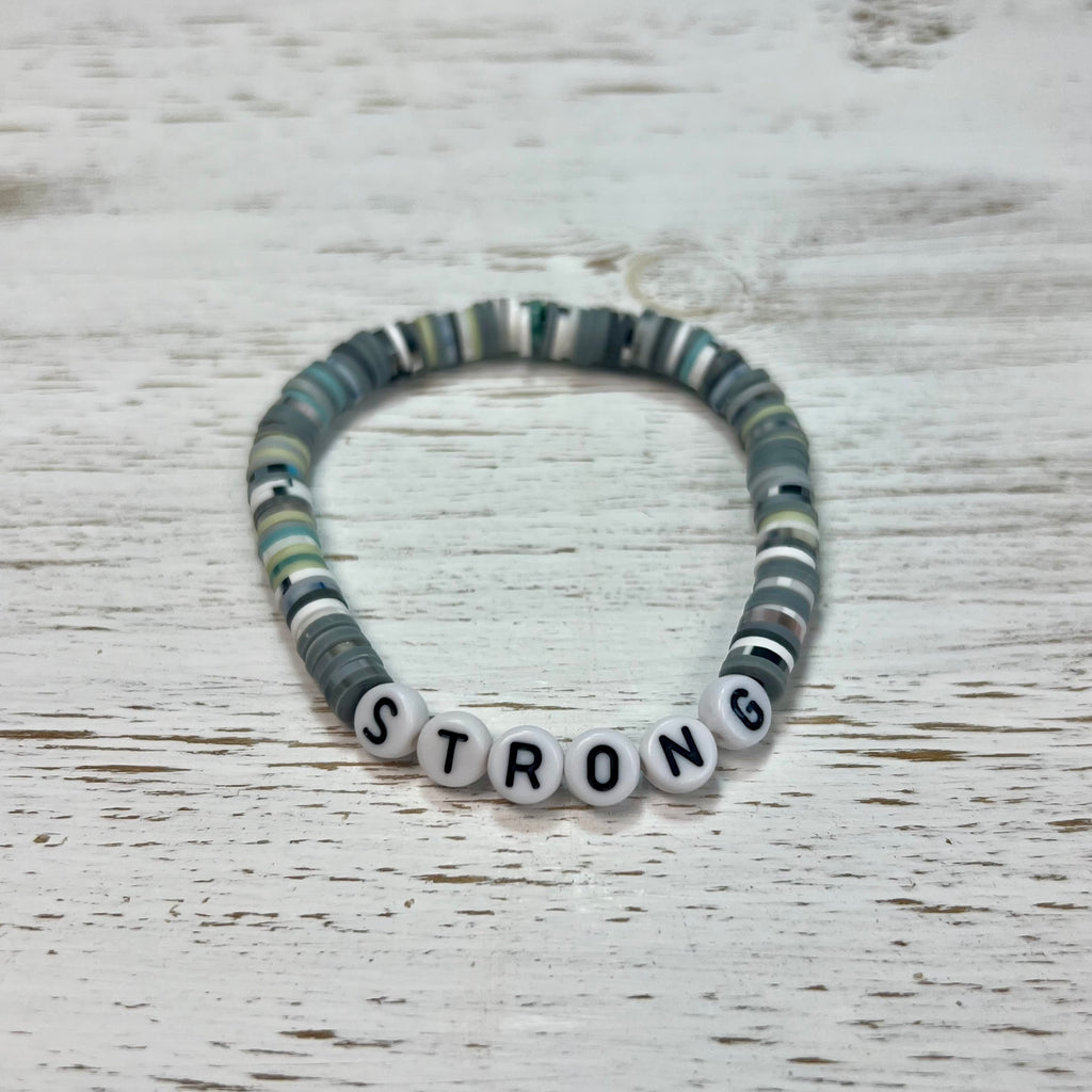 Bracelet with letter beads spelling 'STRONG' on a wooden surface