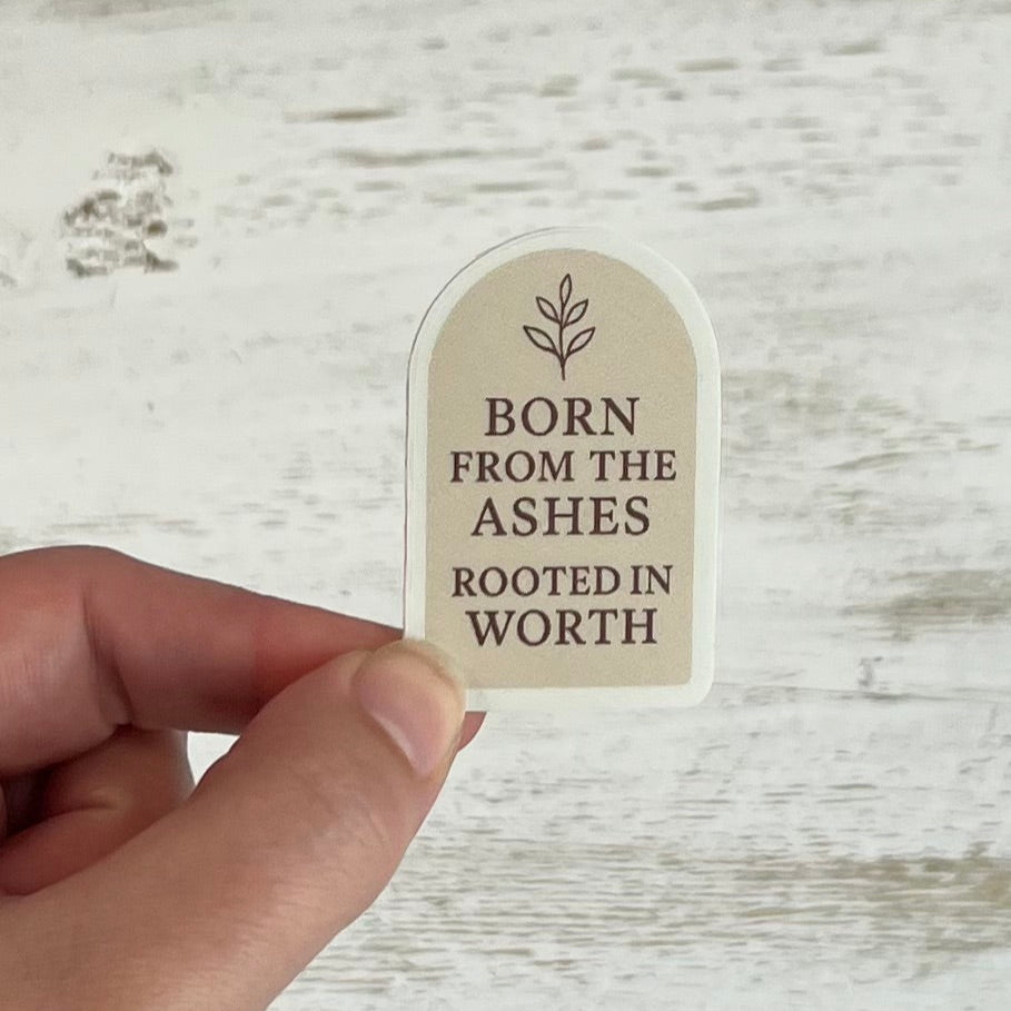 Hand holding a small beige sign with text on a wooden surface