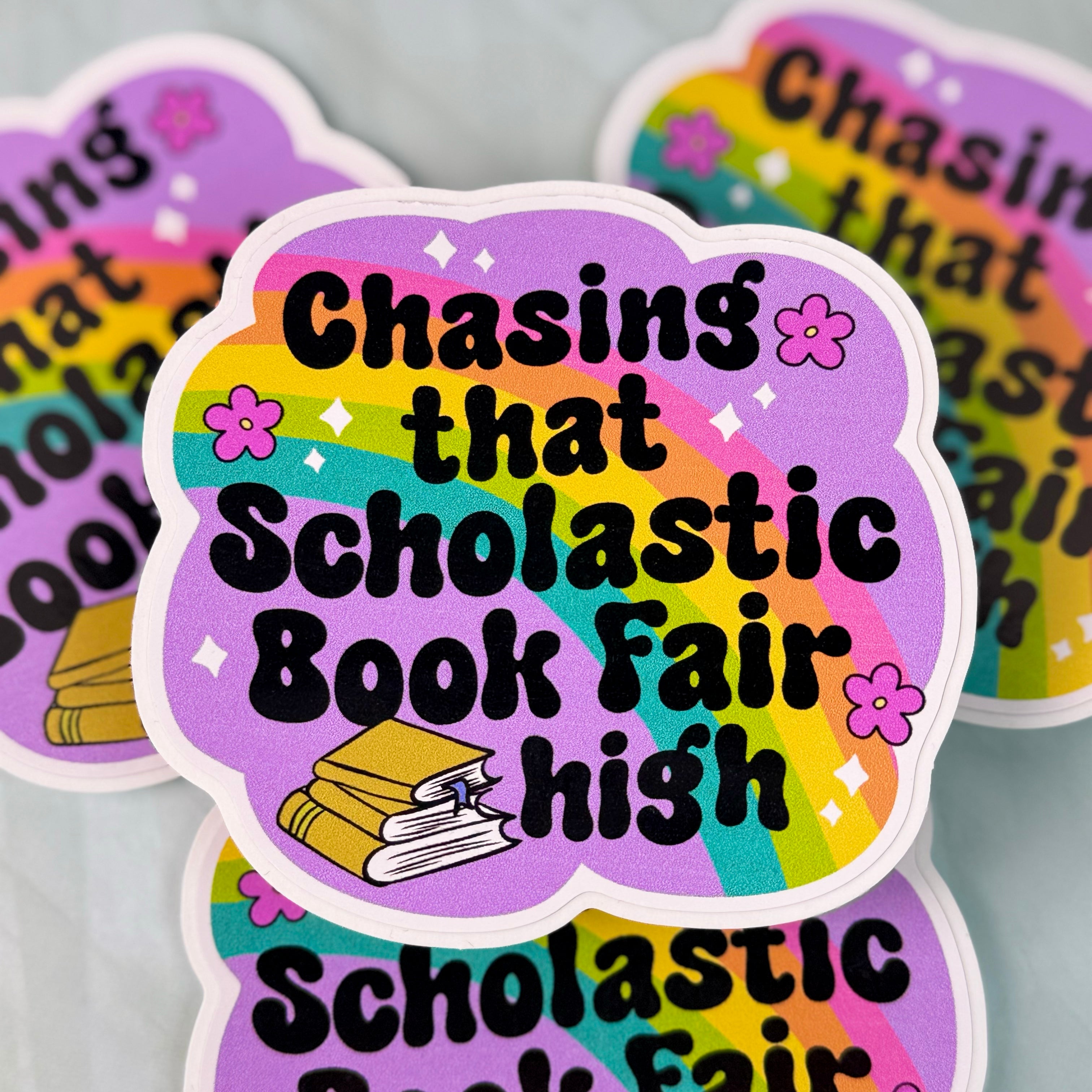 Colorful sticker with text 'Chasing that Scholastic Book Fair high' on a gray background