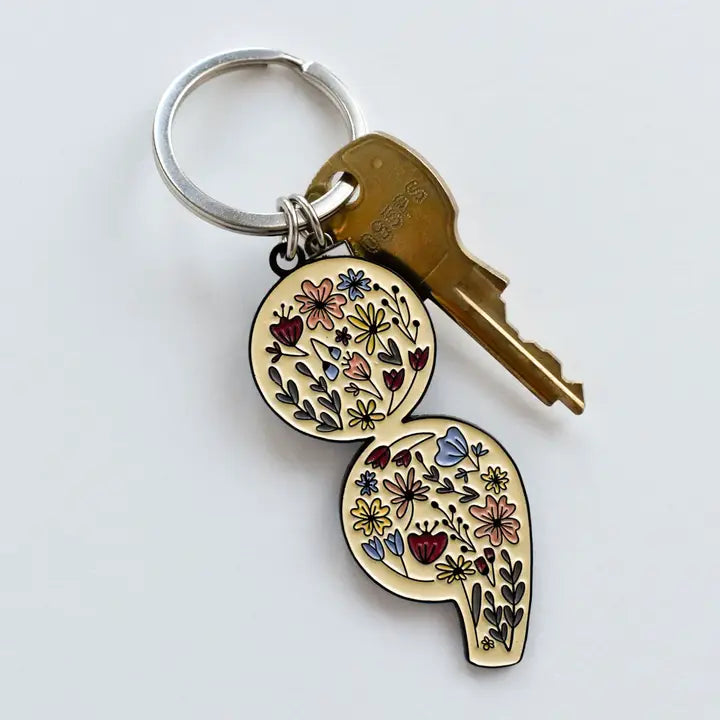 Keychain with floral design attached to a key on a white background