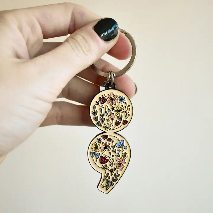 Keychain with floral design held by a hand against a plain background