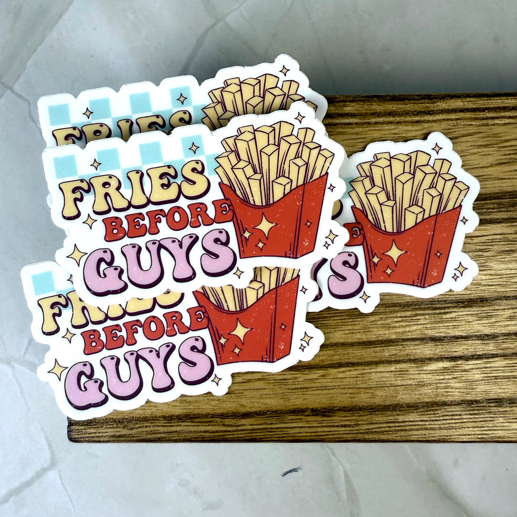 Sticker with 'Fries Before Guys' text design on a wooden surface