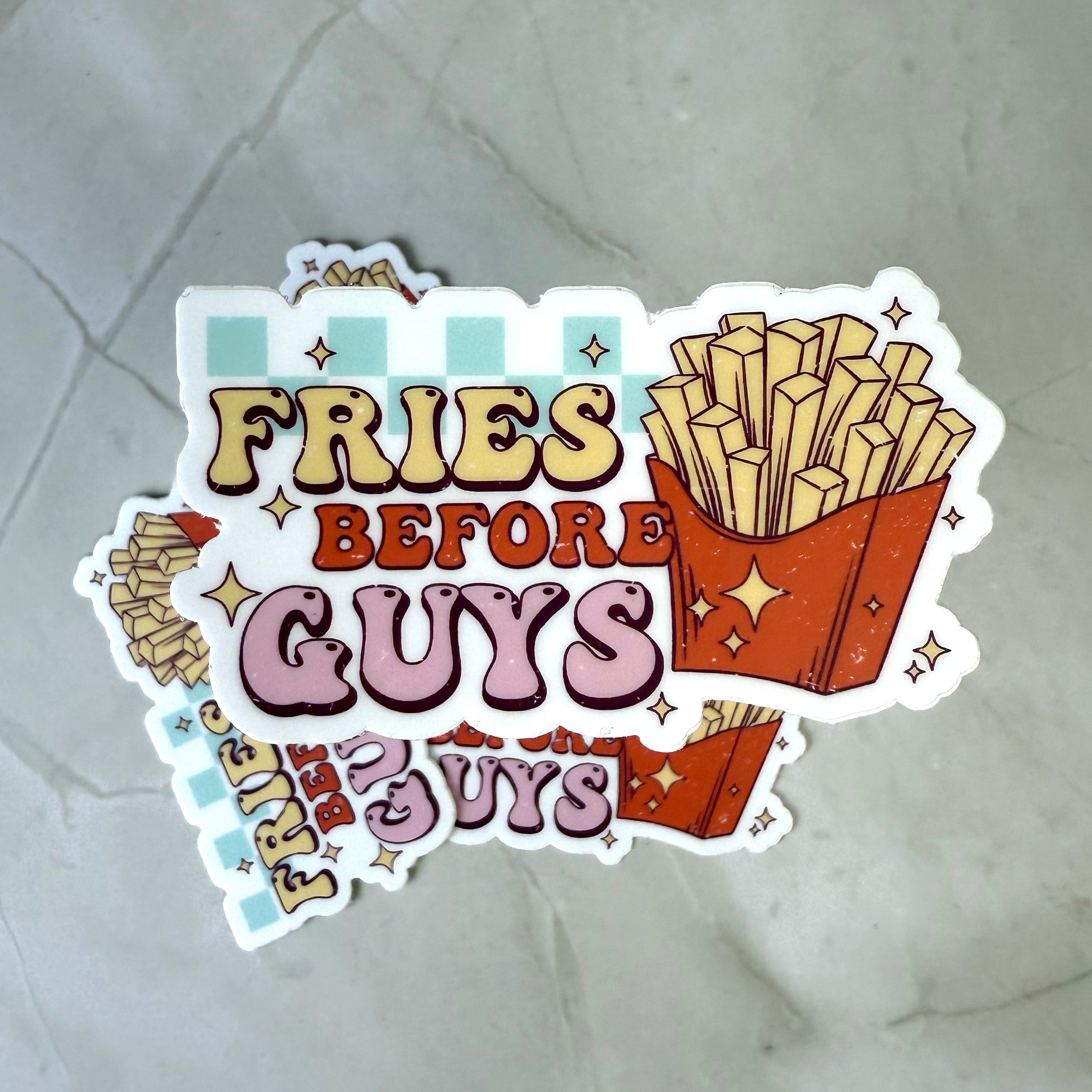 Sticker with 'Fries Before Guys' text and cartoon fries on a textured surface
