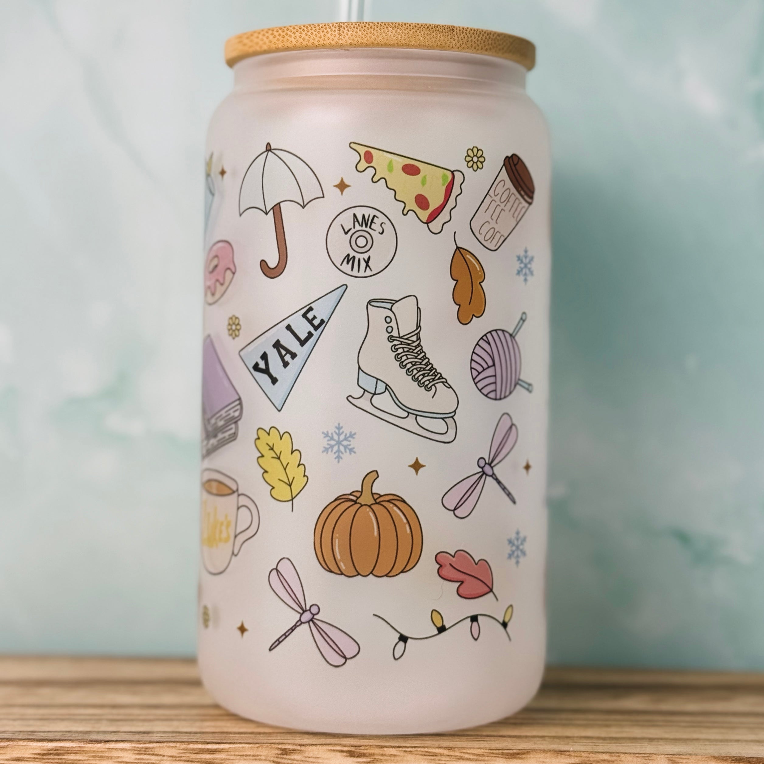 Ceramic can with colorful illustrations on a wooden surface and light blue background