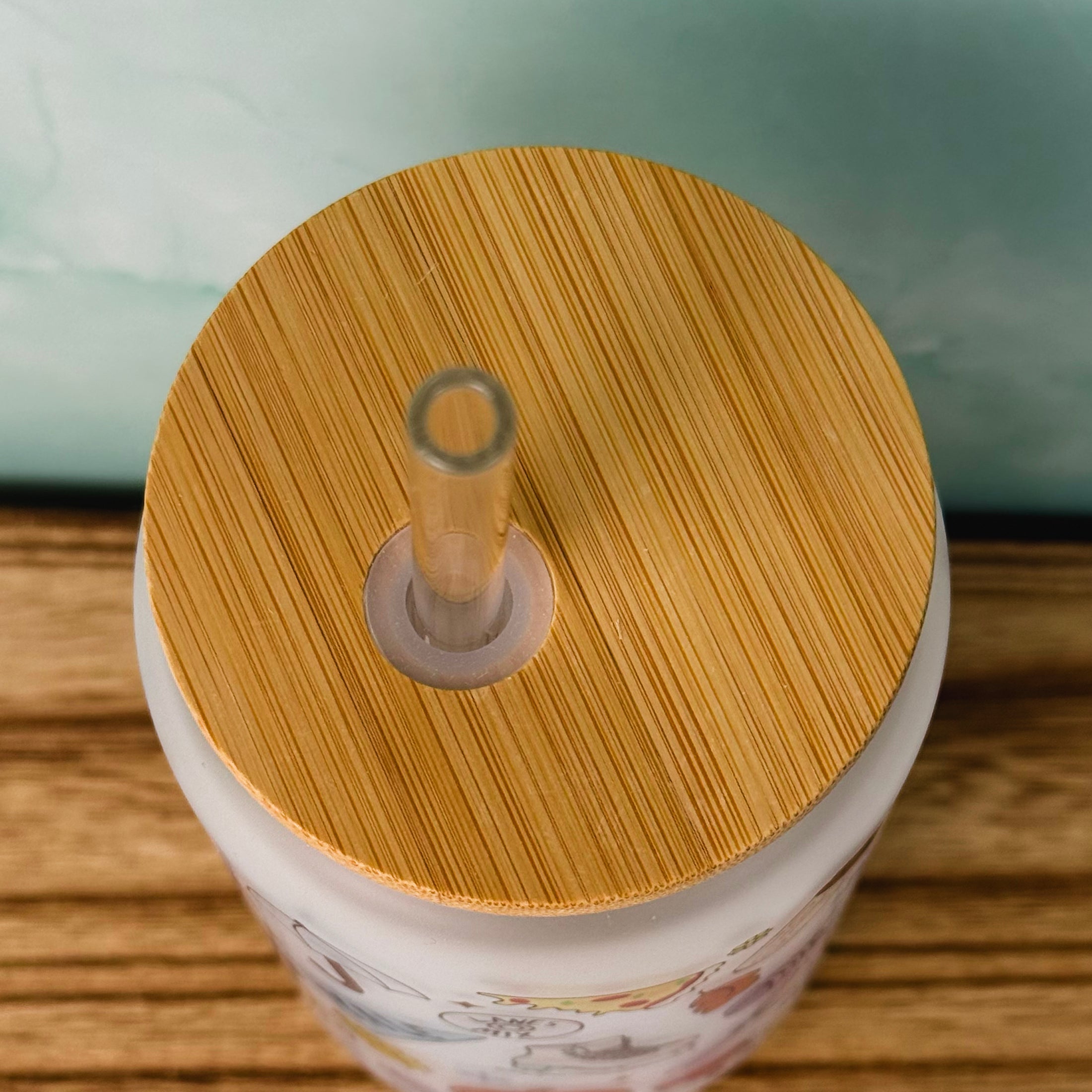 Close-up of a container with a wooden lid and straw on a wooden surface.