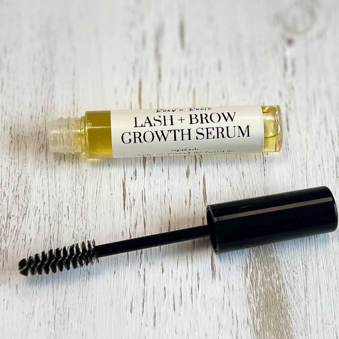 Lash and brow growth serum with applicator on a light wooden surface