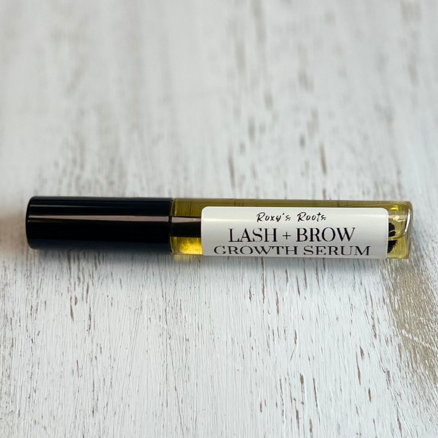 Lash and brow growth serum bottle on a light wooden surface