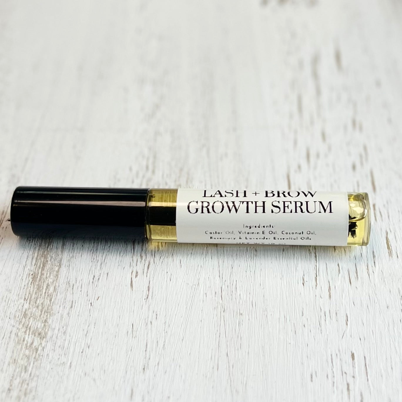 Lash and brow growth serum bottle on a light wooden surface
