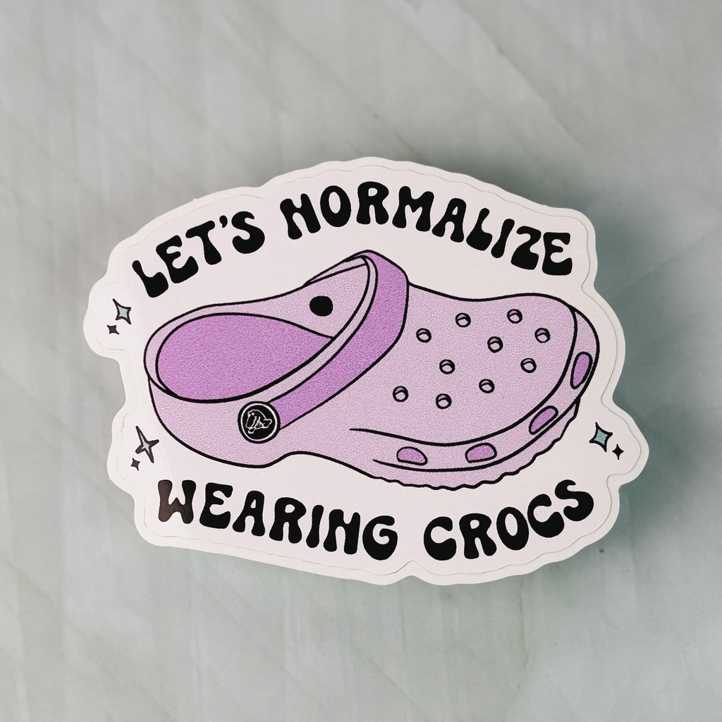 Sticker with a purple croc shoe and text 'Let's Normalize Wearing Crocs' on a light gray background
