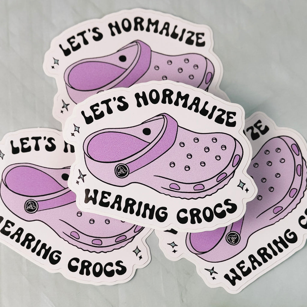 Sticker with purple crocs and text 'Let's Normalize Wearing Crocs' on a gray background