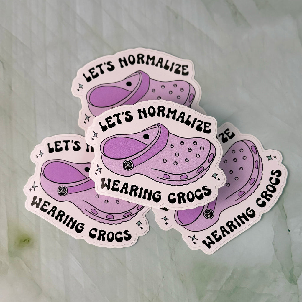 Four stickers with purple crocs and text on a textured surface