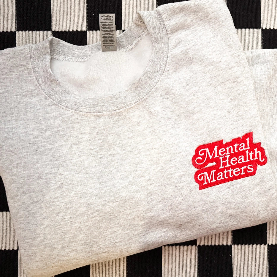 White sweatshirt with 'Mental Health Matters' text on a black and white checkered background