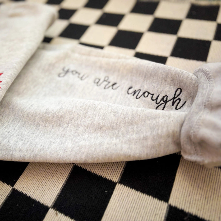 Textile with 'you are enough' embroidery on a checkered background