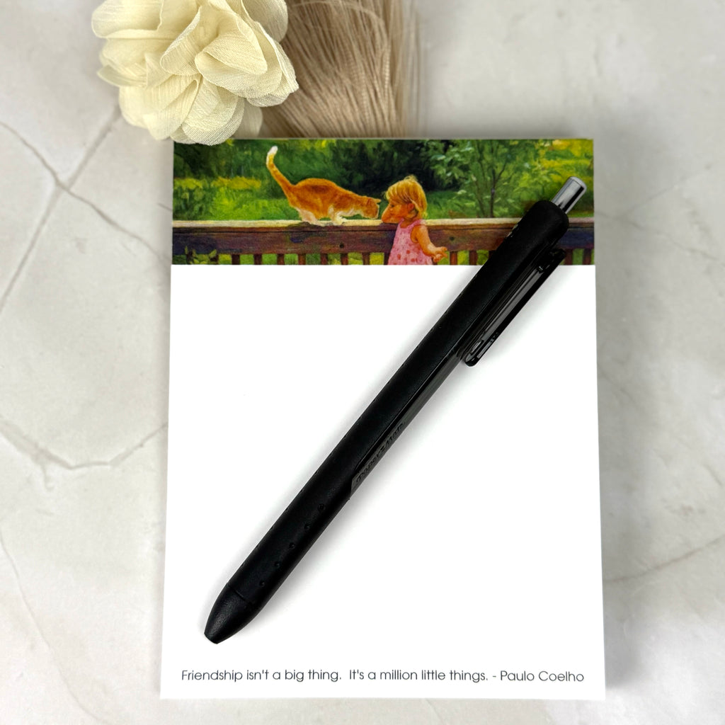Black pen on a notepad with a cat and child illustration and a quote by Paulo Coelho.