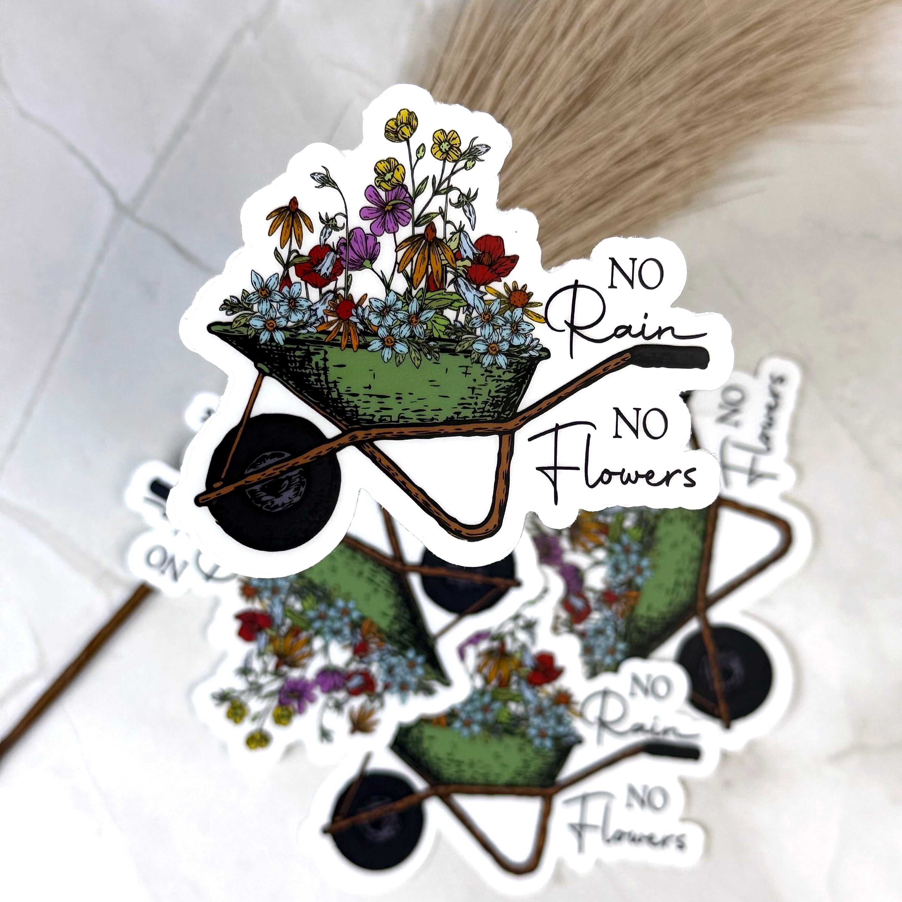 Sticker with a wheelbarrow of flowers and 'No Rain No Flowers' text on a white background.