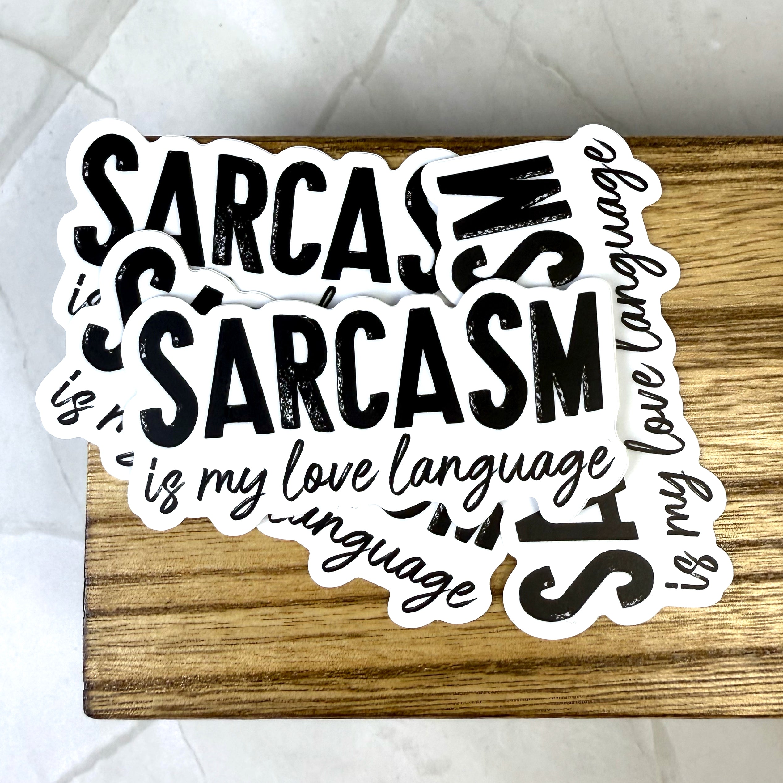 Sticker with text 'Sarcasm is my love language' on a wooden surface