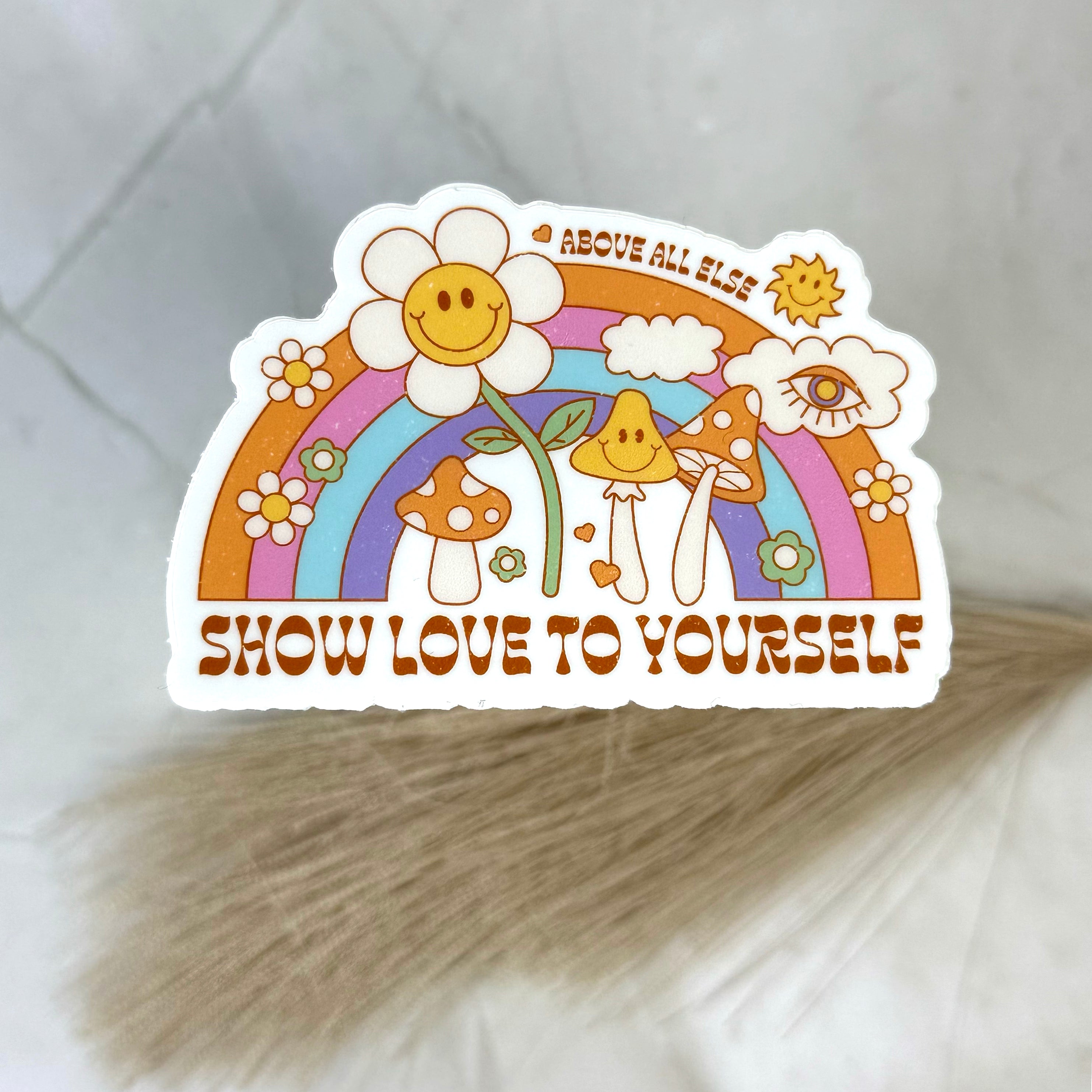 Colorful sticker with a rainbow, flowers, and motivational text on a textured surface.