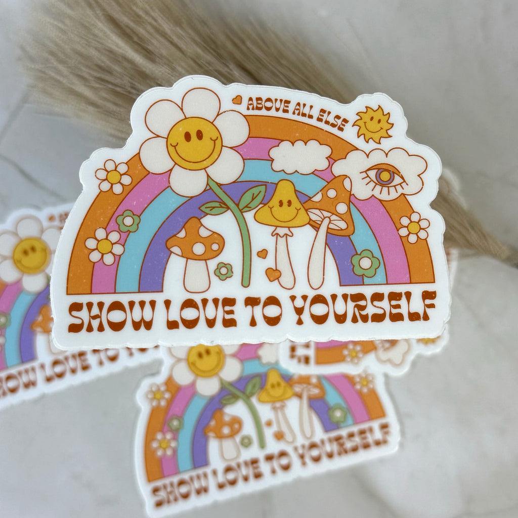 Colorful sticker with rainbow, flowers, and mushrooms with 'Show Love to Yourself' text on a white background.
